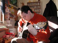 Nick playing his guitar and looking serious about it